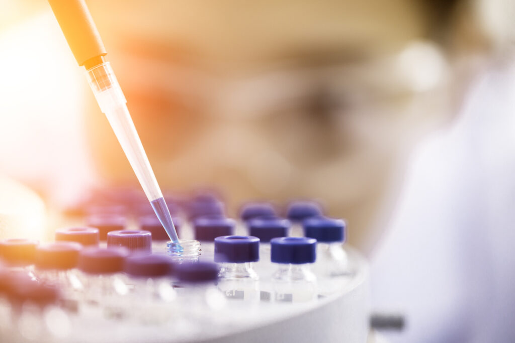 Lab scientist at work pipetting blue liquid into small bottles